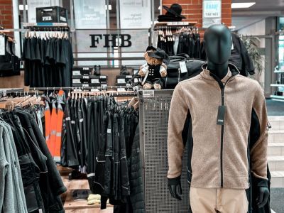 Arbeitskleidungsgeschäft mit schwarzen Kleiderständern und Schaufensterpuppe im Vordergrund Arbeitskleidungsgeschäft mit schwarzen Kleiderständern und Schaufensterpuppe im Vordergrund