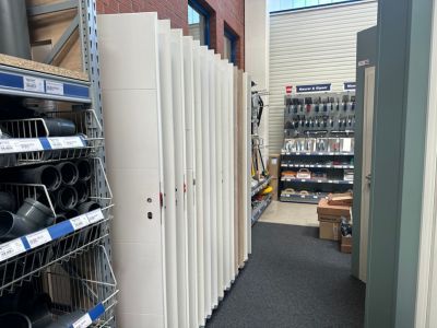 Baumarktgang mit weißen Türen, Regalen voller Werkzeuge und Rohre – typischer Bereich für Bauelemente und Zubehör. Baumarktgang mit weißen Türen, Regalen voller Werkzeuge und Rohre – typischer Bereich für Bauelemente und Zubehör.