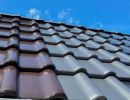 Dachziegel in Braun und Grau installiert unter blauem Himmel, zeigt Auswahl an Materialien für Dachdeckung
