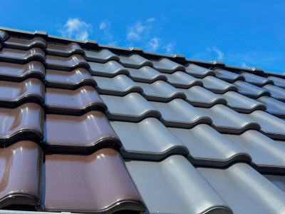 Dachziegel in Braun und Grau installiert unter blauem Himmel, zeigt Auswahl an Materialien für Dachdeckung Dachziegel in Braun und Grau installiert unter blauem Himmel, zeigt Auswahl an Materialien für Dachdeckung