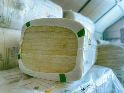 Gelbe Dämmwolle in Plastik verpackt liegt gestapelt im Lager, rechteckige Form für Wärmedämmung im Bau Gelbe Dämmwolle in Plastik verpackt liegt gestapelt im Lager, rechteckige Form für Wärmedämmung im Bau