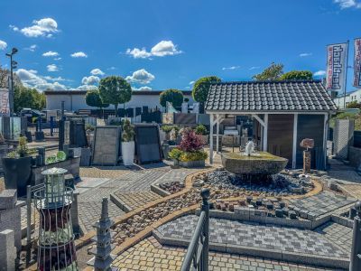 Gartencenter zeigt Pflastersteine, Brunnen und Dekoartikel im Außenbereich unter klarem Himmel Gartencenter zeigt Pflastersteine, Brunnen und Dekoartikel im Außenbereich unter klarem Himmel