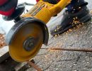 Winkelschleifer schneidet Metallrohr, Funken fliegen – zeigt Einsatz von Maschinen im Bauhandwerk.