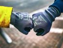 Zwei Personen mit Handschuhen stoßen Fäuste zusammen, symbolisieren Teamgeist, Begrüßung oder Zusammenarbeit