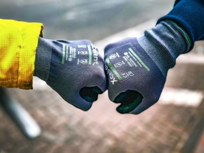 Zwei Personen mit Handschuhen stoßen Fäuste zusammen, symbolisieren Teamgeist, Begrüßung oder Zusammenarbeit