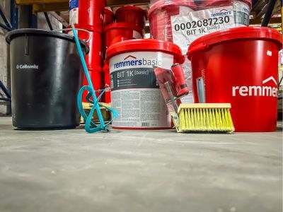 Eimer und Werkzeuge stehen bereit auf Lagerboden, zeigen Bauchemieprodukte für professionelle Anwendungen