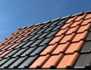 Dach mit Ziegeln in Rot, Grau und Braun unter blauem Himmel zeigt Vielfalt an Materialien für Dachdeckung