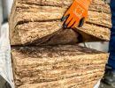Hand hält Glaswolle-Isolierung, zeigt Material zur Wärmedämmung von Gebäuden, weich und faserig im Griff