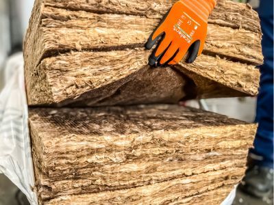 Hand hält Glaswolle-Isolierung, zeigt Material zur Wärmedämmung von Gebäuden, weich und faserig im Griff