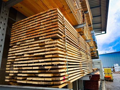 Holzlatten ordentlich gestapelt unter Dach, zeigen Lagerung von Baumaterialien für spätere Verwendung