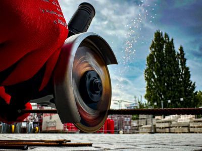 Winkelschleifer schneidet Metallstäbe, Funken fliegen, zeigt Einsatz von Maschinen im Bauhandwerk draußen