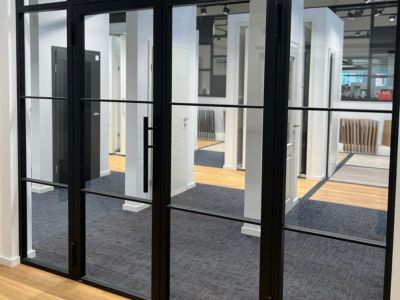 Modernes Büro mit Glaswänden und Türen, klare Linien und helle Beleuchtung zeigen funktionale Raumgestaltung