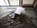 „Eine Person glättet frischen Betonboden – zeigt Arbeitsschritte beim fachgerechten Einbau und Ausgleich von Böden