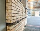Gestapelte Holzplanken in Lagerhalle, geordnetes Material zeigt Vielfalt und Einsatzmöglichkeiten im Holzbau