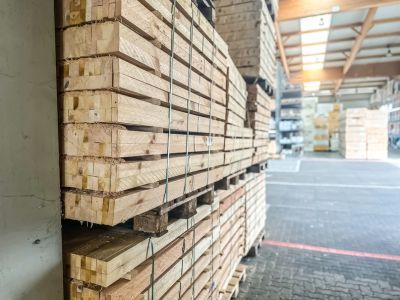 Gestapelte Holzplanken in Lagerhalle, geordnetes Material zeigt Vielfalt und Einsatzmöglichkeiten im Holzbau