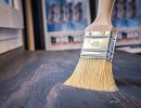 Pinsel  liegt auf dunklem Holz, zeigt Anwendung von Farben oder Lasuren im Innenbereich